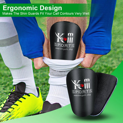 Black shin guards with KM Sports logo being worn on a grass field.